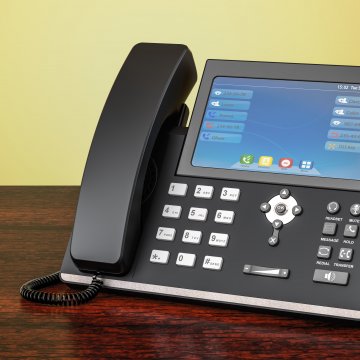 1-voip voip services voip phone on brown desk yellow wall in the background